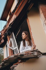 shot of a young woman looking at the damage to her house after an earthquake