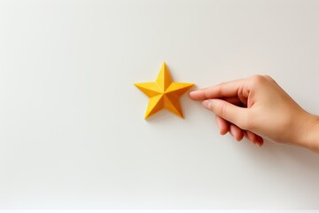 Obraz premium Female hand holding a paper star on a white background. Top view