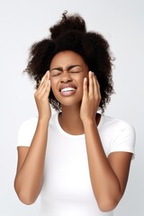 shot of a happy young woman holding her head in pain against a white background