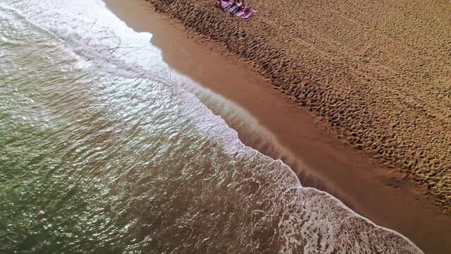 Birdseye view of Cabopino beach in Calahonda, Spain, tilting up and moving backwards over the sea