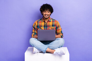 Full body portrait of positive cheerful man sit podium use wireless netbook isolated on purple...