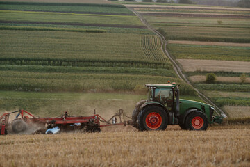 Fototapeta na wymiar A tractor plows a wheat field. The concept of the work of a farmer and harvest.