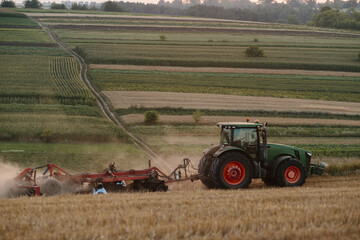 A tractor plows a wheat field. The concept of the work of a farmer and harvest.