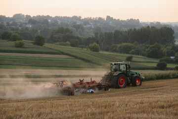 A tractor plows a wheat field. The concept of the work of a farmer and harvest.