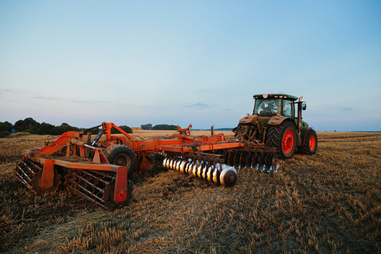 A tractor with a large disc harrow for tillage. Farmer work concept.