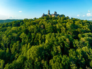 Medieval castle in Braunfels, Hesse, Germany, with many later additions, on the top of a hill covered with green forest. Aerial drone view in summer in sunset light