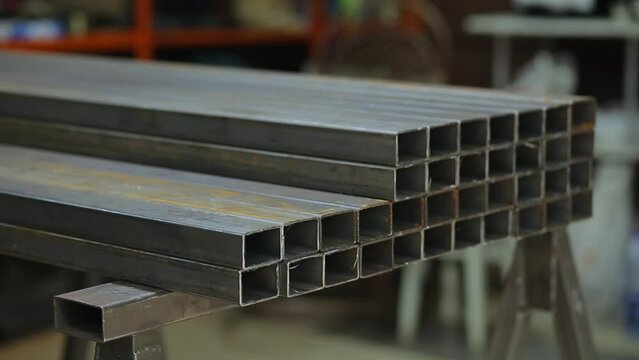 Welder or blacksmith put metal iron square pipe profiles from warehouse for project.