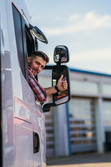 Truck driver sitting in his truck showing thumbs up. Trucker occupation. transportation services.