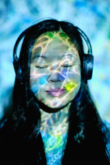 Asian woman with neon lights on face listening to music