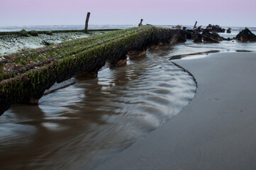 The remains of an old shipwreck on the beach at low tide