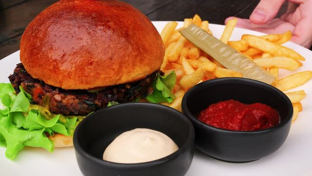 Junk food nutrition on plate is burger, french fries, sauces. Approaching shot of plate with junk food nutrition in restaurant. Concept don't eat much junk food nutrition to safe your health.