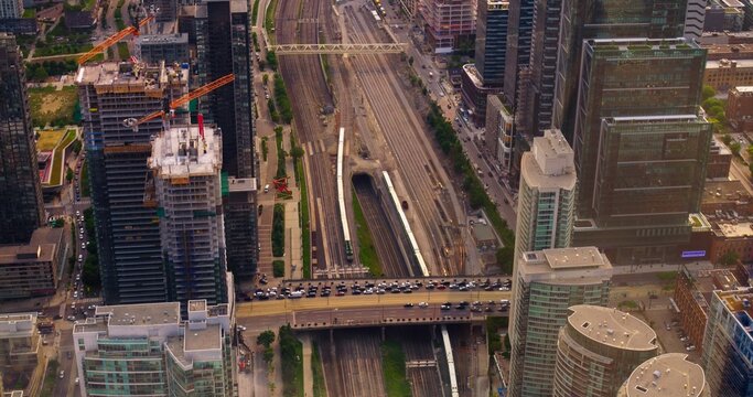 City heartbeat from above, capturing the intricate network of roads and railway tracks with trains in motion. Witness the synergy as cars navigate the bustling intersections alongside railway lines