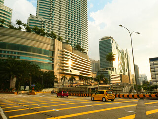 Obraz premium A wide road in Kuala Lumpur during a sunny day with palm trees and skyscrapers in the background