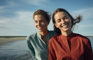 Two woman wearing the same shirt smiling in on a small beach