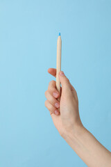 Female hand holding a pencil on a blue background