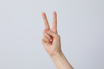 Female hand showing two fingers on a light background