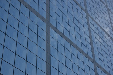 Vitres d'immeuble carrées avec reflets du ciel bleu et des nuages