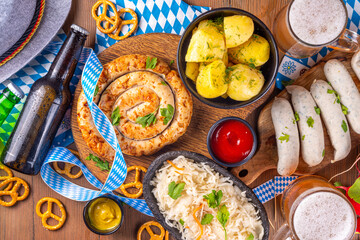  Oktoberfest munich traditional festival menu foods - bavarian sausages, pretzels, potato, sauerkraut, beer bottle and mug,  Background flyer for Oktoberfest invitation on old wooden table