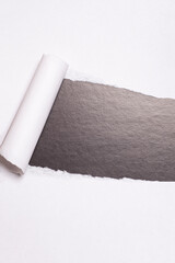 Torn paper with opening showing black background.