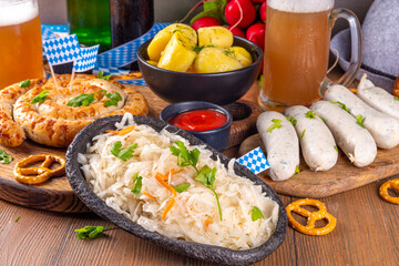  Oktoberfest munich traditional festival menu foods - bavarian sausages, pretzels, potato, sauerkraut, beer bottle and mug,  Background flyer for Oktoberfest invitation on old wooden table