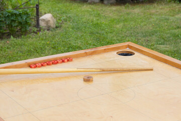 Close-up of a part of the playing field of a novuss table with a cue stick and chips
