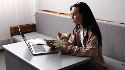 Caucasian joyful happy beautiful young woman sitting on sofa in modern living room with cute puppy...