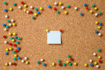 Empty sticky paper note with pushpins and blank space on cork board background.