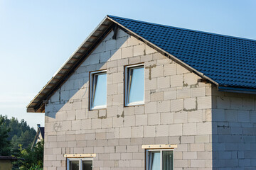 Country village house made of unplastered cellular blocks and a metal roof