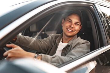 Young smiling man sitting in a car with open window