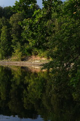 Sunny day. You can see the river and the reflection of the trees in the river.