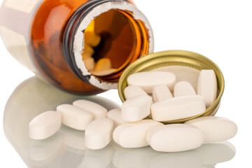 Several medical pills with glass bottle, macro, isolated on white background.