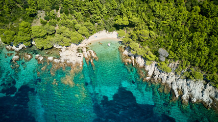 aerial view of small beach with turquoise water and rocky shore