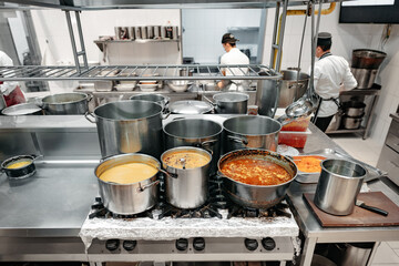 Food preparing in metal pots on the stove at professional kitchen