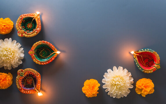 Happy Diwali - Clay Diya lamps lit during Diwali, Hindu festival of lights celebration. Colorful traditional oil lamp diya on blue background