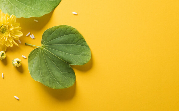 Happy Dussehra. Yellow flowers, green leaf and rice on yellow paper background. Dussehra Indian Festival concept.