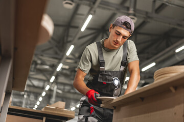 Young carpenter making wood furniture while working in joinery