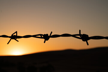 Sunset on the hill behind the barbed wire