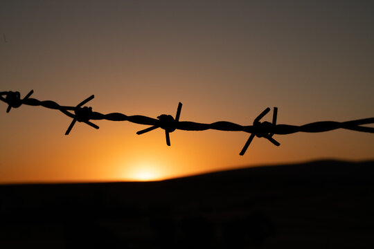 Sunset on the hill behind the barbed wire