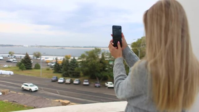 A young woman takes a view of the city on her phone. A traveler shoots a video with a smartphone in a tourist place