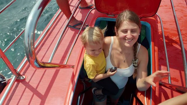 Happy smiling woman with baby son walking up the stairs on tourist submarine. Family holiday, summer vacation and tourism.