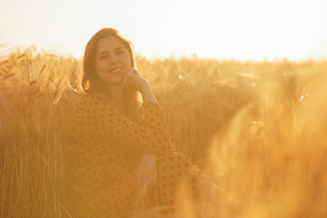 Close-up portrait of beautiful young woman in a countryside field. Female face in the rays of sunset. Freedome and happiness concept.