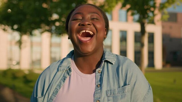 African American woman student girl lady at city outdoors near university college smiling laughing laud humorous news joke smile laugh happy hilarious ridiculous having fun funny situation reaction