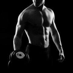 Fototapeta na wymiar Strong, fit and sporty bodybuilder man with a dumbbell over black background