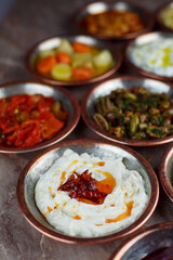 Spicy yogurt paste appetizer in a bronze bowl with other appetizers