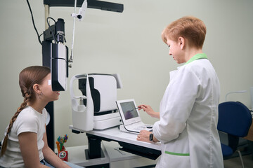 Girl with two pigtails is in clinic at appointment with ophthalmologist