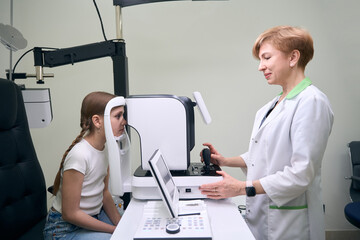 Ophthalmologist examines eyes of young female patient on modern equipment
