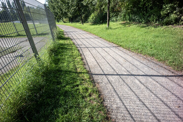 Metal fence and the shadow on a footpath