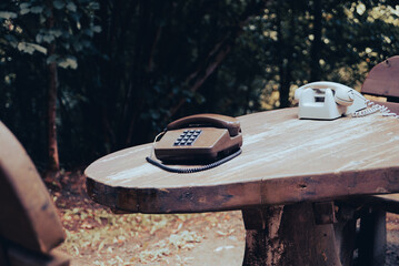 Old analog telephone on a wooden table in the forest