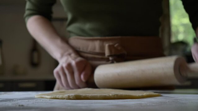mom makes the dough and rolls it out with a rolling pin on table