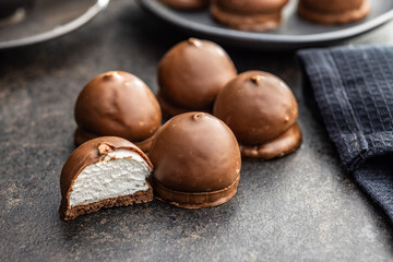 Chocolate covered marshmallows. Sweet dessert on black table.